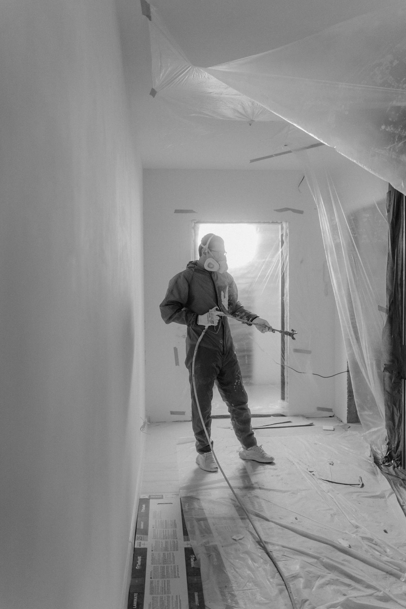Black and white image of a person painting a room, focusing on renovation and improvement.